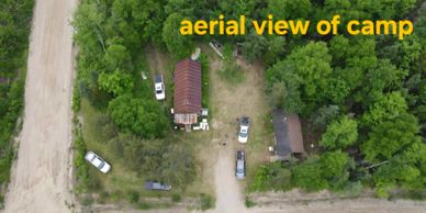 Aerial view of a small camp surrounded by trees and vehicles.