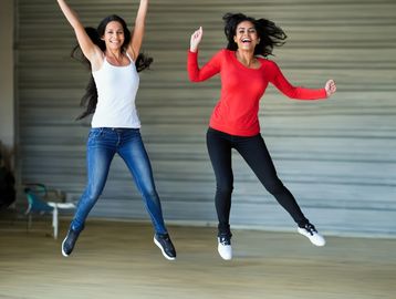 Image of 2 women joyfully jumping up in the air