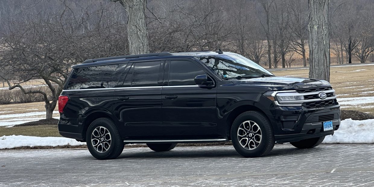Black Ford SUV parked on a wintery road with bare trees in the background.