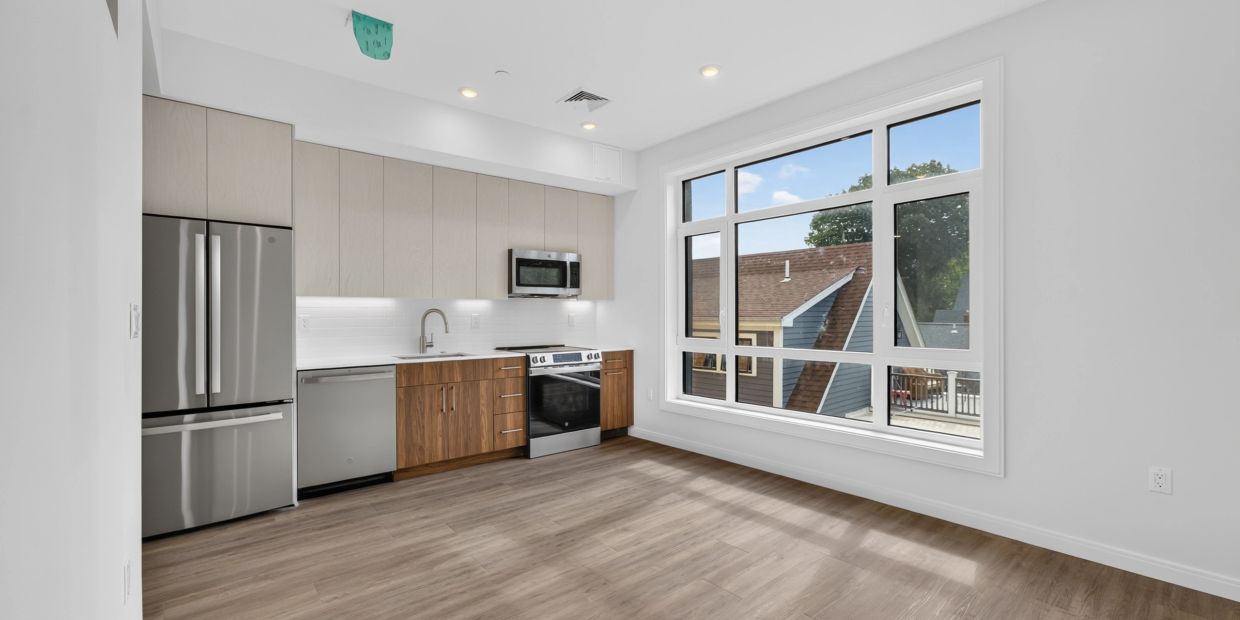Modern kitchen with large window and wood flooring.