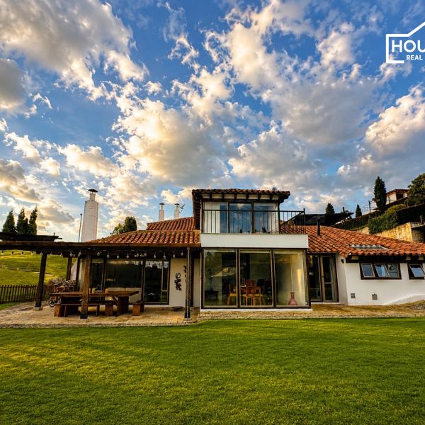 Beautiful house with large windows under a dramatic cloudy sky.