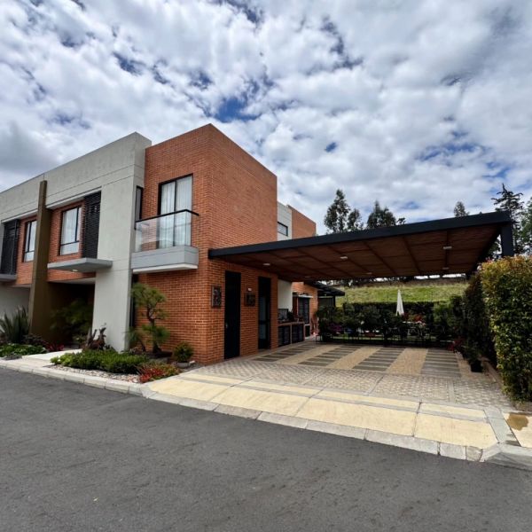 Modern two-story brick and concrete house with a covered carport and landscaped front yard.