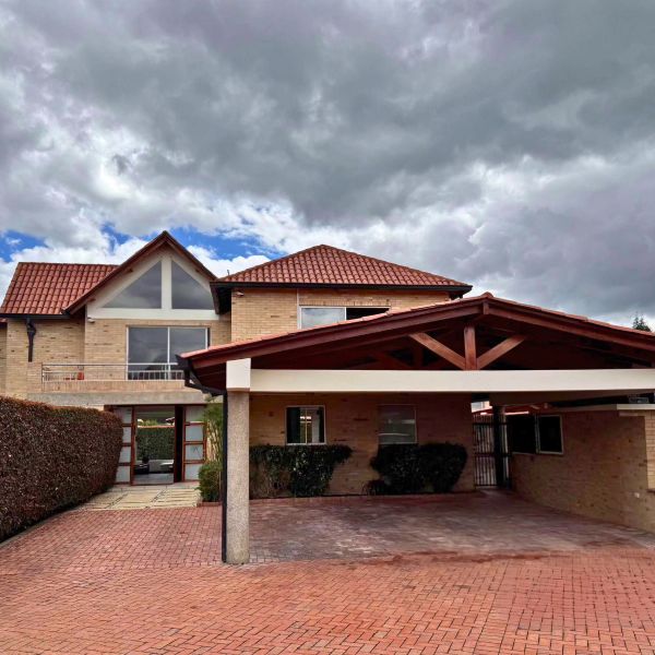 Modern two-story house with brick exterior and tiled roof under cloudy skies.