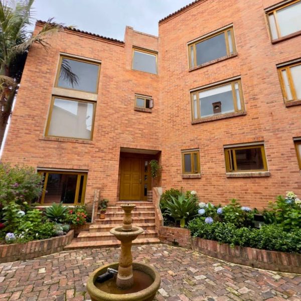 Brick house with large windows and a central fountain in the courtyard.
