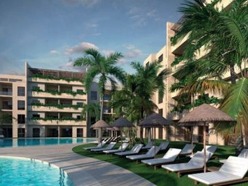 Resort poolside with lounge chairs and palm trees under a clear sky.