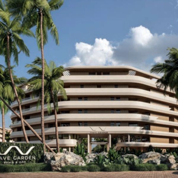 Modern multi-story building surrounded by palm trees under a blue sky.