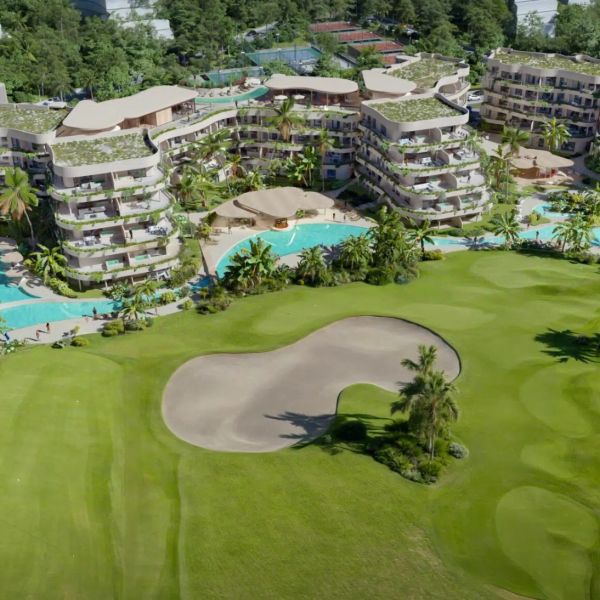 Luxury resort with green rooftops next to a golf course and pool.