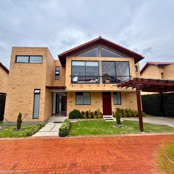 Modern two-story brick house with large glass windows and a wooden pergola.