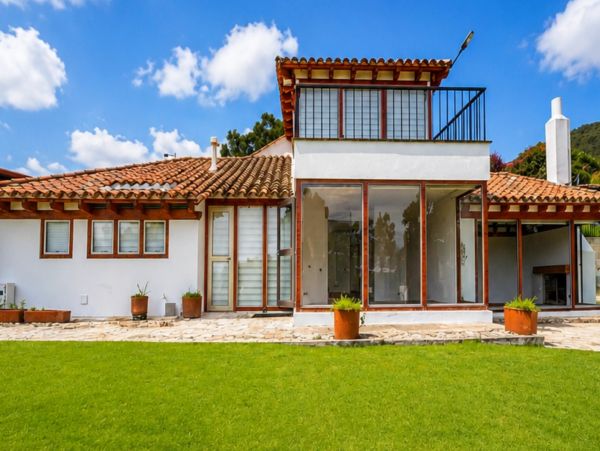 Modern house with large windows and a tiled roof under a blue sky.