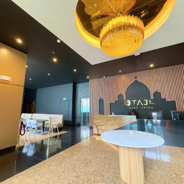 Modern hotel lobby with chandelier and reception desk.