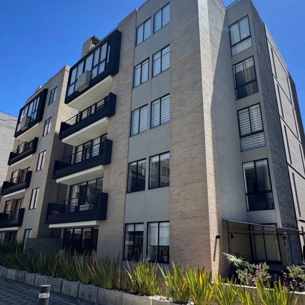 Modern apartment building with balconies and large windows under a clear blue sky.