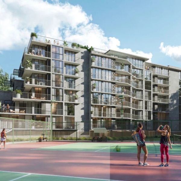 Modern apartment building with tennis courts and people enjoying outdoor activities.