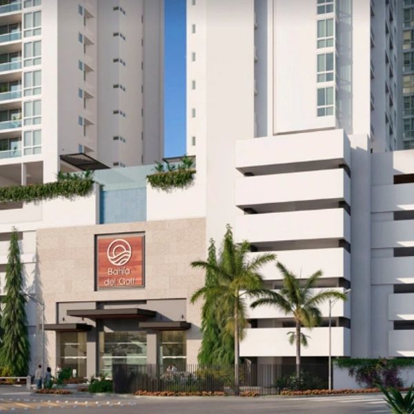 Modern residential building entrance with palm trees and a sign reading 'Bahía del Golf.'