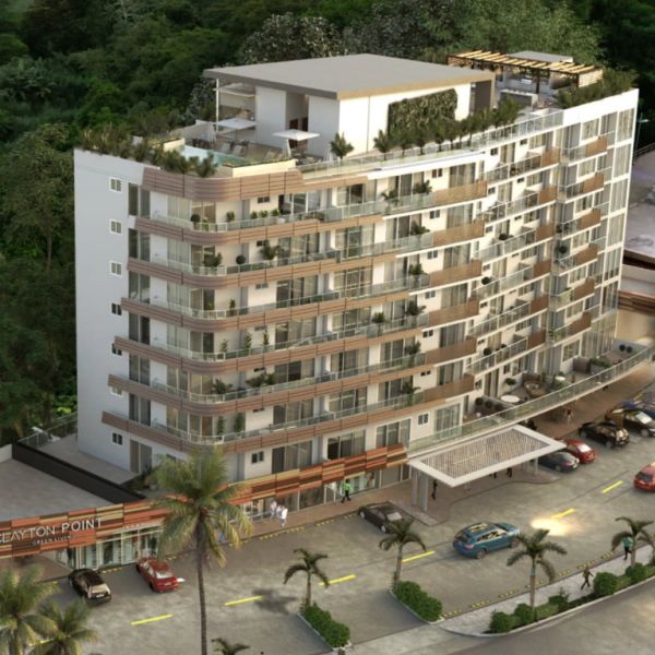 Modern multi-story apartment building with balconies and rooftop terrace surrounded by greenery.