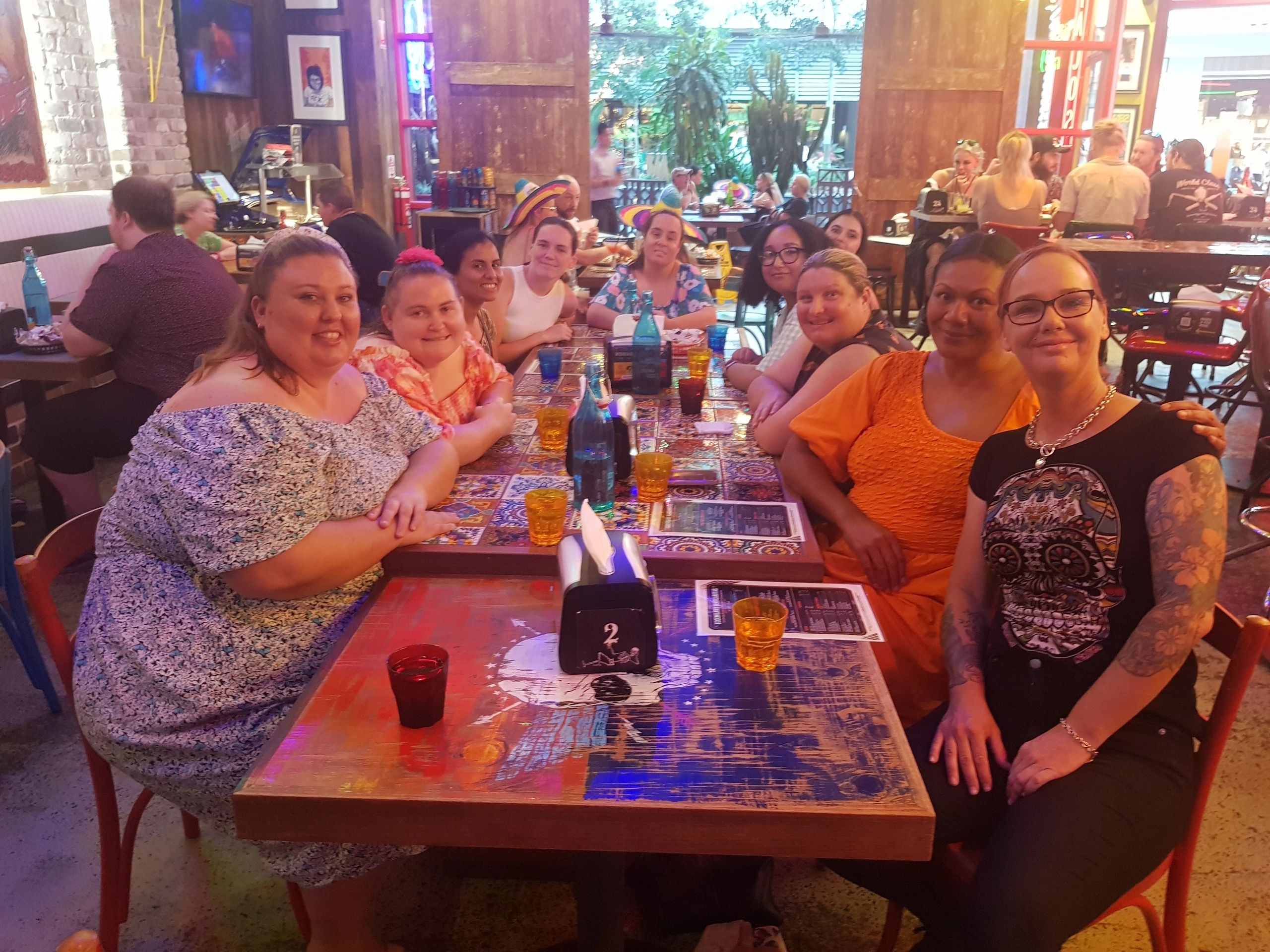 10 people sitting at a dining table smiling.