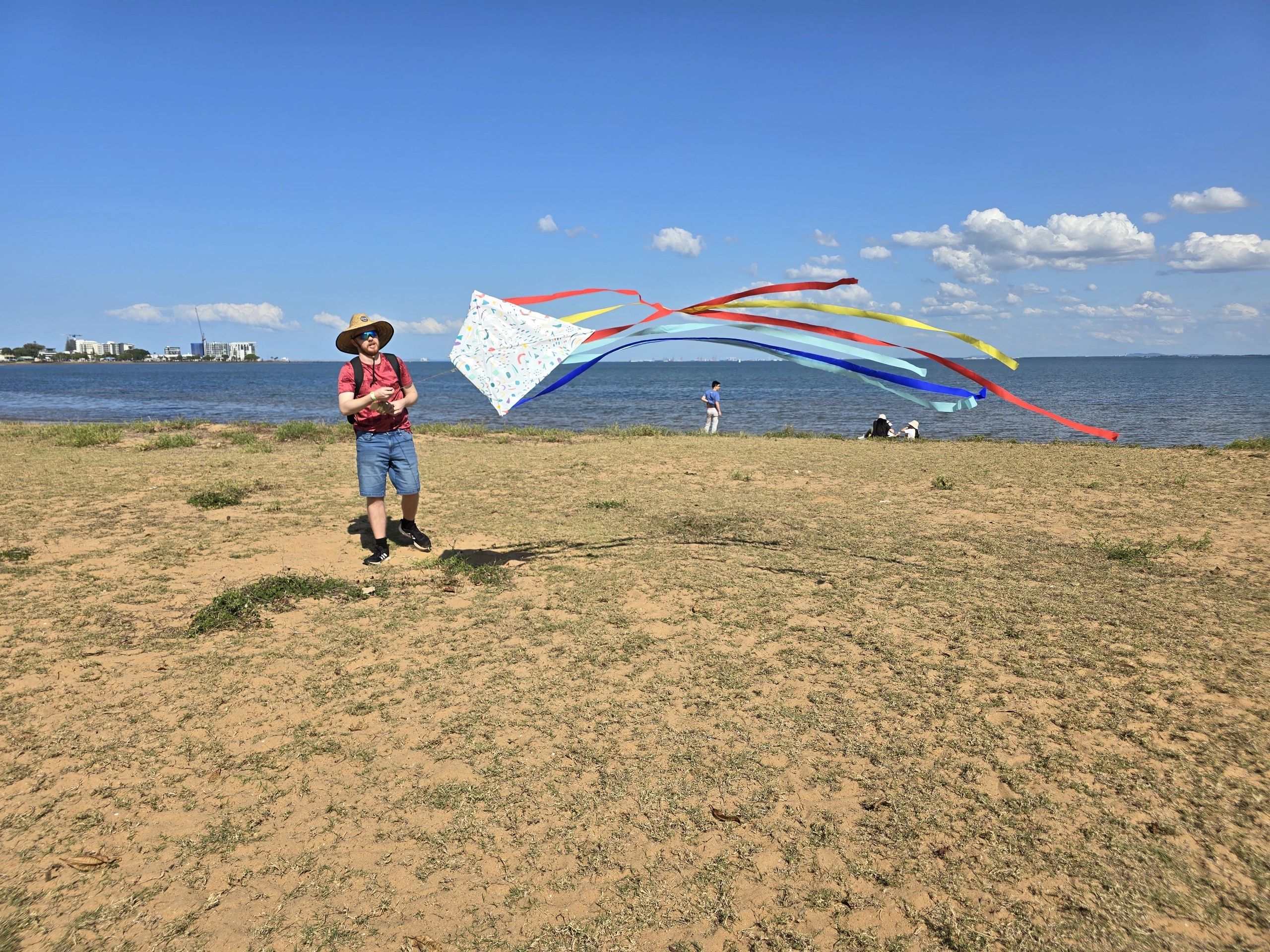 A man standing on the beach flying a kite.