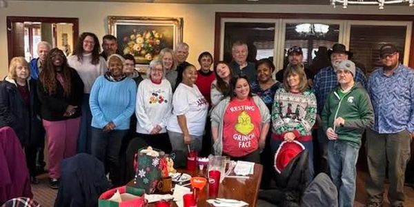 A diverse group of people posing in a cozy room with holiday decorations.