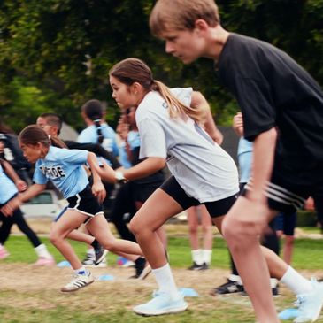 Young athletes sprinting on a grassy field during a race.