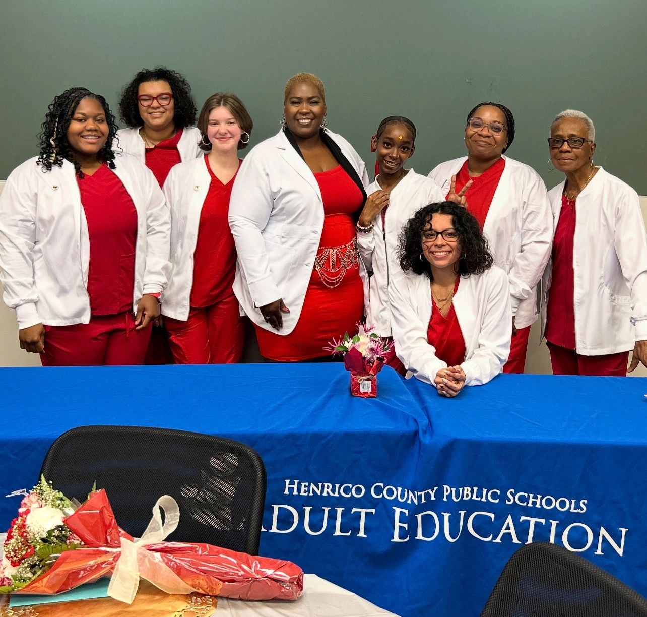 Group of smiling women in red and white attire at Henrico County Public Schools Adult Education event.