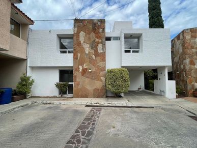 Modern white house with stone accents and a driveway under a cloudy sky.