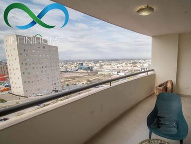 Balcony view overlooking a cityscape with a chair and table.