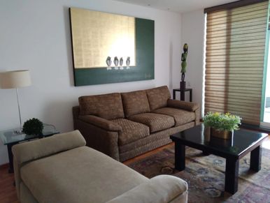 Cozy living room with a brown sofa, beige chaise lounge, and a black coffee table.