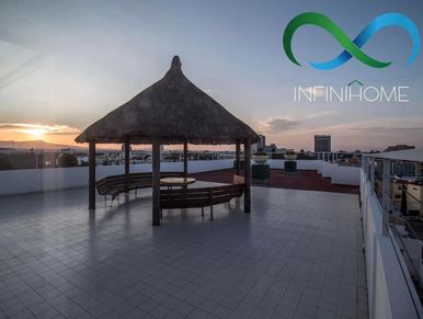 Rooftop patio with a thatched gazebo and sunset view.