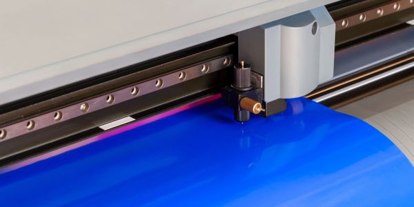 A printer head printing vivid blue material on a roll.