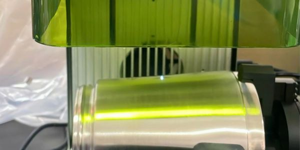 A silver can is being scanned under a green light.