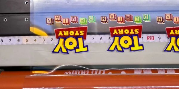 A ruler with Toy Story logos and colorful alphabet blocks spelling 'AND DEMAND' and 'NAN'.