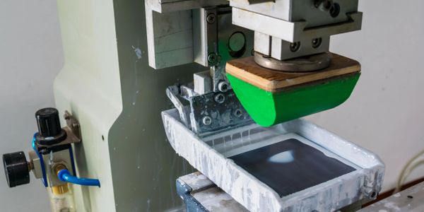 Screen printing machine applying ink onto a screen frame.