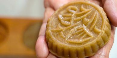 Hand holding a traditional mooncake with intricate patterns.