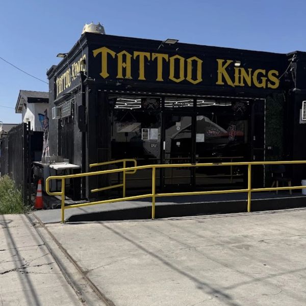 Black building with yellow "TATTOO KINGS" sign and yellow railings.
