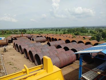 Large rusty metal cylinders stored outdoors in an industrial yard.