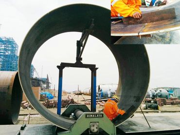 Worker in orange safety gear inspecting a large industrial pipe at a construction site.