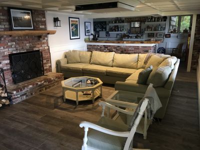 Cozy living room with a large beige sectional sofa and brick fireplace.