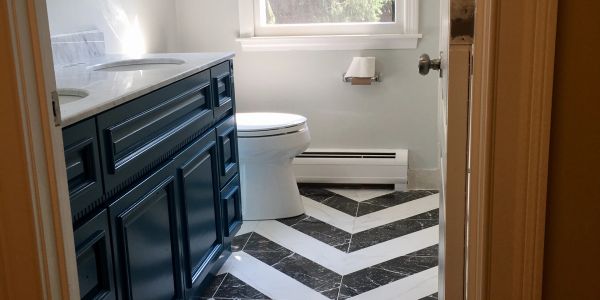 Bathroom with navy blue vanity and chevron patterned black and white floor tiles.