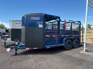Blue livestock trailer parked on gravel.