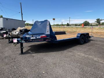 Flatbed trailer parked on gravel with clear sky.