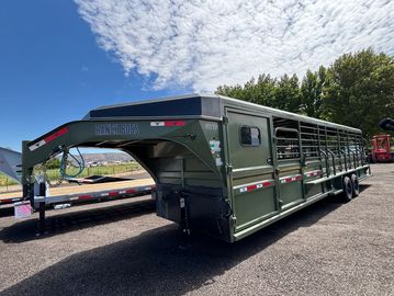 Green livestock trailer with gooseneck hitch parked outdoors.