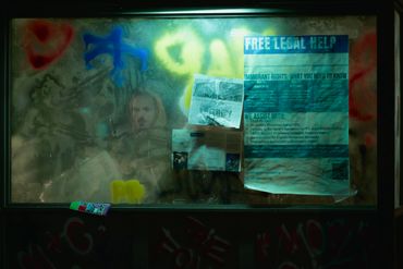 A foggy window covered with graffiti and flyers offering free legal help.