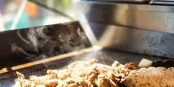 Steam rises from cooked meat on a hot grill.