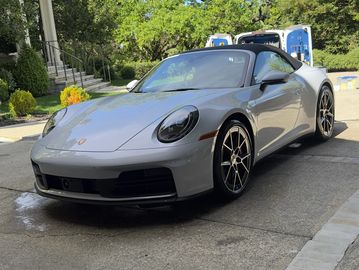 Silver Porsche sports car parked outdoors on a sunny day.