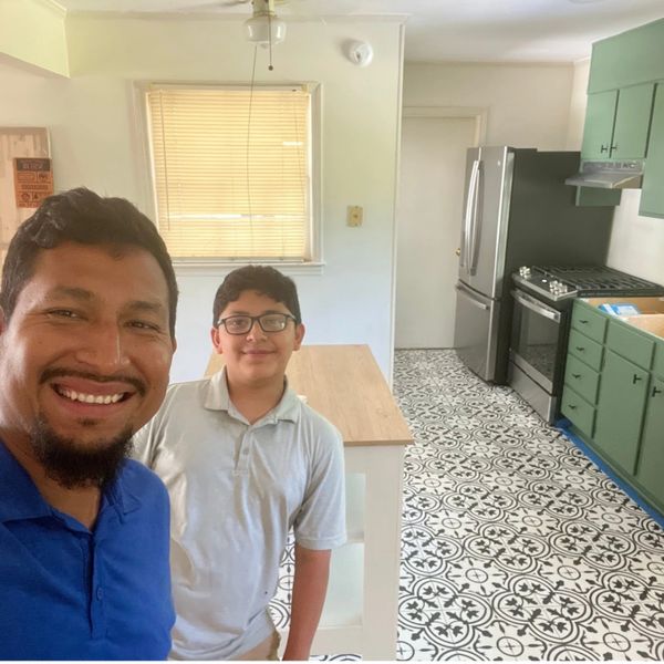 Two people smiling in a modern kitchen with patterned tile floor.