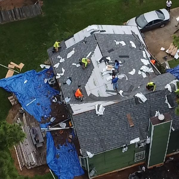Workers installing a roof on a house.