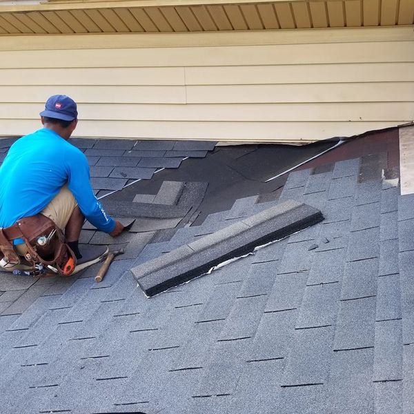 Worker installing shingles on a roof.
