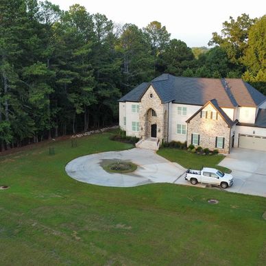 Large two-story house with a circular driveway and white truck.