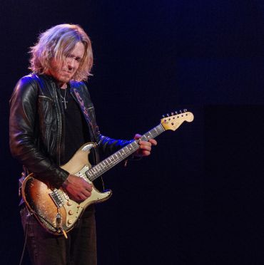 Man playing electric guitar on stage.