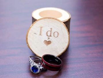 Two rings with a wooden disc engraved 'I do' and a heart symbol.