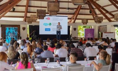 Conferencia con público en salón amplio y techo de madera.